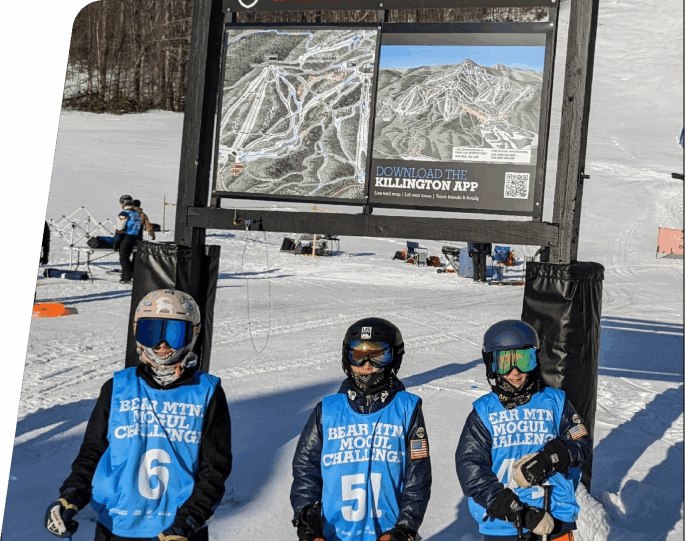Three children in ski gear by trail map.