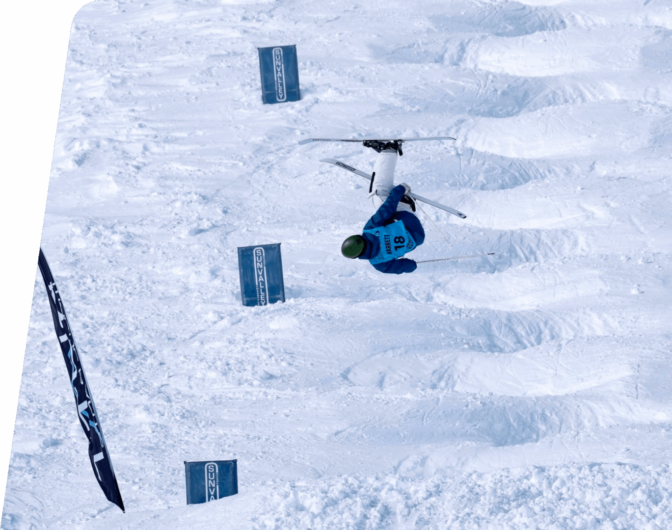 Skier performing trick on snowy mogul course.
